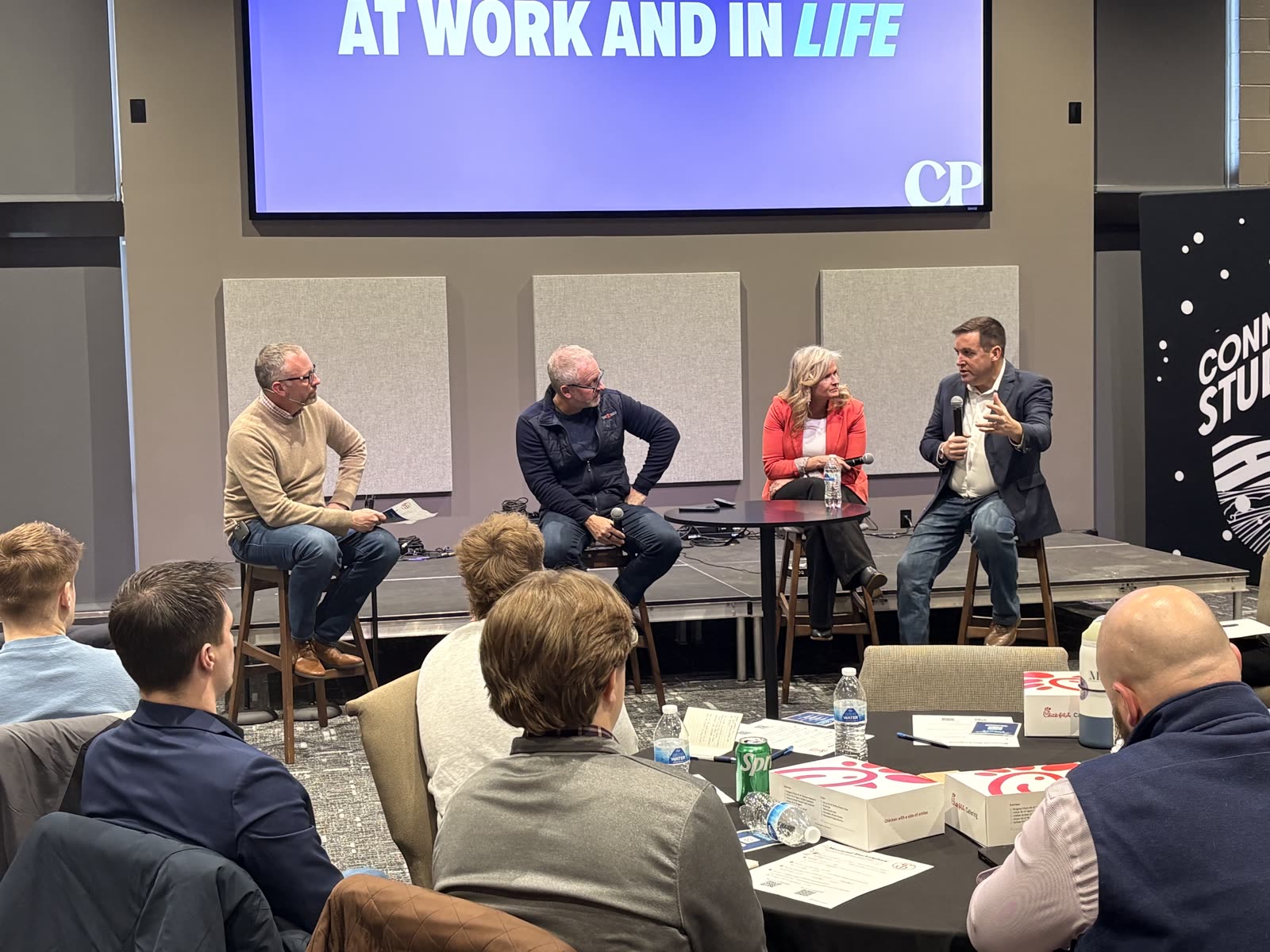 A panel discussion on leadership at work and in life, four speakers seated on stage.